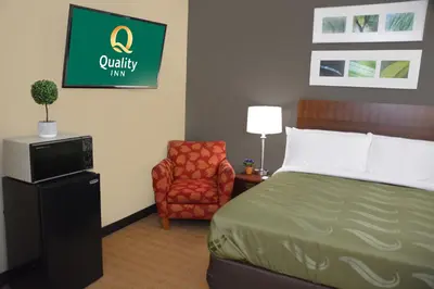 a hotel room with a bed and a chair at Quality Inn & Suites Dublin in Dublin