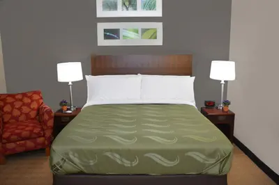 a bedroom with a bed and a chair and two lamps at Quality Inn & Suites Dublin in Dublin