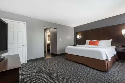a bedroom with a large bed and a flat screen tv at Hawthorn Extended Stay by Wyndham Columbus West in Columbus