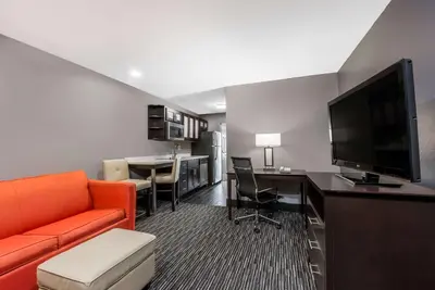 a living room with a couch and a desk with a television at Hawthorn Extended Stay by Wyndham Columbus West in Columbus