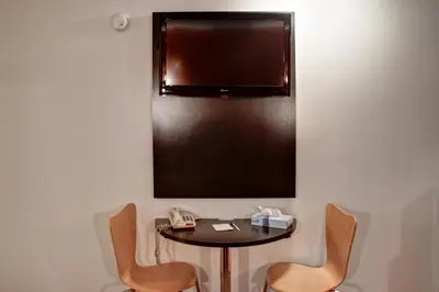 a small table with two chairs and a tv on a wall at Americas Best Value Inn Heath-Newark in Heath