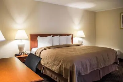 a hotel room with a bed and a table and two lamps at Baymont by Wyndham Youngstown in Youngstown