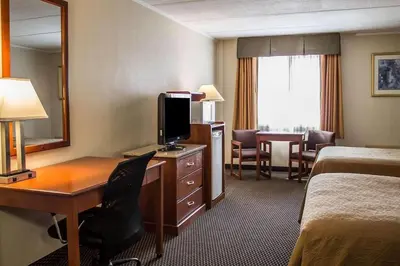 a hotel room with a desk and a bedroom at Baymont by Wyndham Youngstown in Youngstown