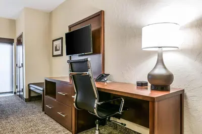 a hotel room with a desk with a chair and a lamp at Comfort Suites Florence - Cincinnati South in Florence