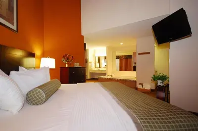 a bedroom with a large bed with a television on the wall at Baymont by Wyndham Delaware in Delaware
