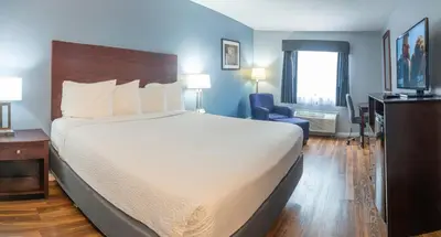a hotel room with a large bed and a chair at Baymont by Wyndham Delaware in Delaware