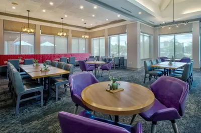 a dining room with tables and purple chairs at Hilton Garden Inn Dayton/ Beavercreek in Beavercreek