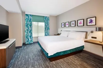 a hotel room with a bed and a flat screen tv at Hilton Garden Inn Dayton/ Beavercreek in Beavercreek