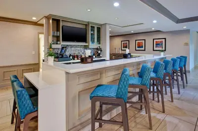 a bar with blue chairs in a room at Hilton Garden Inn Dayton/ Beavercreek in Beavercreek