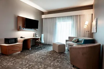 a hotel room with a desk and a couch at Courtyard Cincinnati Airport South/Florence in Florence