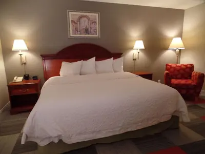 a hotel room with a large bed and a chair at Hampton Inn Bowling Green in Bowling Green