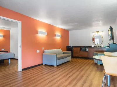 a living room with orange walls and a couch at Motel 6-Columbus, OH - OSU in Columbus