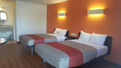 two beds in a hotel room with orange walls at Motel 6-Columbus, OH - OSU in Columbus