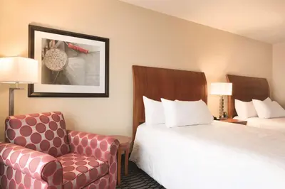 a hotel room with two beds and a chair at Hilton Garden Inn Akron-Canton Airport in North Canton