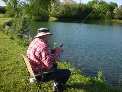 a man sitting in a chair fishing on a lake at Wilmington Camping Resort in Wilmington
