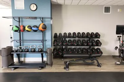 a fitness room with a rack of dumbbells and a clock at Hampton Inn Kent/Akron Area in Kent