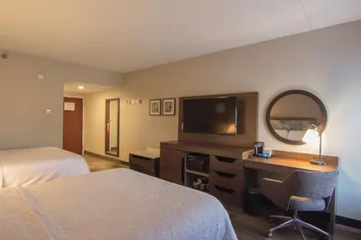 a hotel room with two beds and a desk with a television at Hampton Inn Medina in Medina