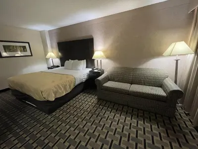 a hotel room with a bed and a chair at Quality Inn & Suites Cincinnati Downtown Area in Cincinnati
