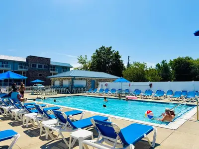 a swimming pool with blue chairs and people in it at Put-in-Bay Waterfront Condo #103 in Put-in-Bay