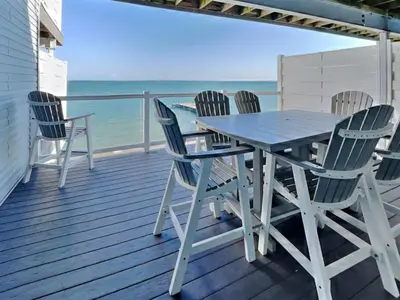 a table and chairs on a deck with the ocean at Put-In-Bay Waterfront Condo #108 in Put-in-Bay