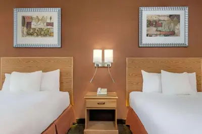 two beds in a hotel room with two lamps at Days Inn by Wyndham Columbus Fairgrounds in Columbus