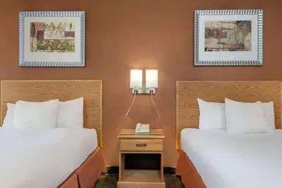 two beds in a hotel room with two lamps at Days Inn by Wyndham Columbus Fairgrounds in Columbus