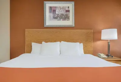 a bed with white pillows and a phone next to it at Days Inn by Wyndham Columbus Fairgrounds in Columbus
