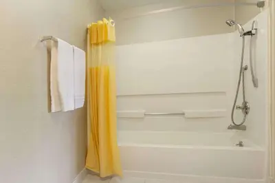 a bathroom with a shower with a yellow shower curtain at Days Inn by Wyndham Columbus Fairgrounds in Columbus