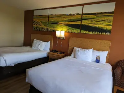 two beds in a hotel room with a painting on the wall at Days Inn by Wyndham Columbus Fairgrounds in Columbus