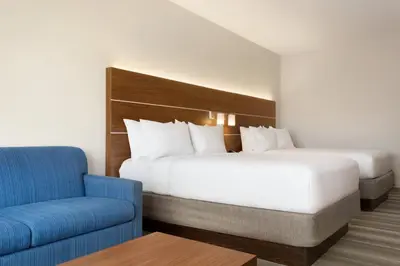 a hotel room with a bed and a blue chair at Holiday Inn Express & Suites - Cincinnati South - Wilder by IHG in Wilder