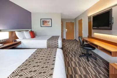 a hotel room with two beds and a flat screen tv at Microtel Inn & Suites by Wyndham Pittsburgh Airport in Robinson Township