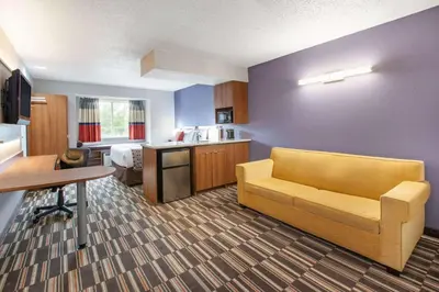 a living room with a couch and a bed in a room at Microtel Inn & Suites by Wyndham Pittsburgh Airport in Robinson Township