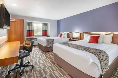 a hotel room with two beds and a desk at Microtel Inn & Suites by Wyndham Pittsburgh Airport in Robinson Township