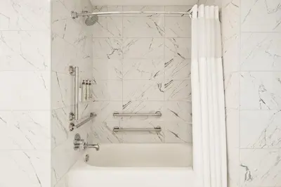 a bathroom with a shower with white marble walls at Hotel Cleveland Autograph Collection in Cleveland