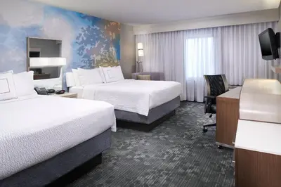 a hotel room with two beds and a desk at Courtyard Cleveland Airport North in North Olmsted