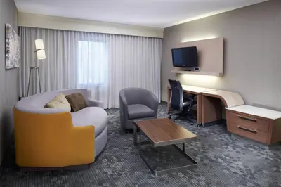 a hotel room with a couch and a desk with a computer at Courtyard Cleveland Airport North in North Olmsted
