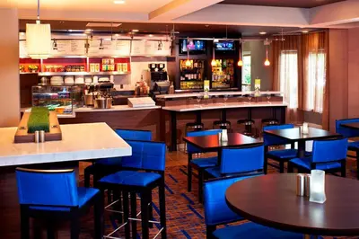 a restaurant with blue chairs and tables and a bar at Courtyard Cleveland Airport North in North Olmsted
