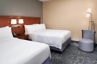 a hotel room with two beds and a chair at Courtyard Columbus Dublin in Dublin