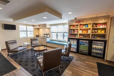 a waiting room with a drink refrigerator and chairs at TownePlace Suites Columbus Airport Gahanna in Gahanna