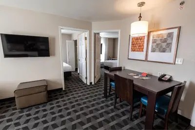 a hotel room with a desk and a room with a bedroom at TownePlace Suites Columbus Airport Gahanna in Gahanna