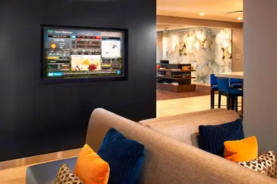 a living room with a couch and a tv on a wall at Courtyard Cincinnati Covington in Covington