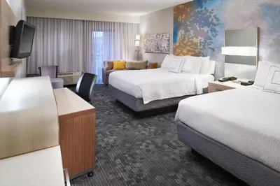 a hotel room with two beds and a couch at Courtyard Cincinnati Covington in Covington