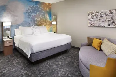 a hotel room with a bed and a couch at Courtyard Cincinnati Covington in Covington