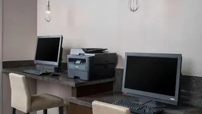 two computer monitors sitting on a desk with a printer at Sonesta ES Suites Cincinnati - Sharonville West in Sharonville