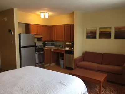 a living room with a couch and a kitchen at Hawthorn Extended Stay by Wyndham Cincinnati NE Mason in Mason