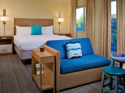 a hotel room with a bed and a blue chair at Sonesta Simply Suites Dublin Columbus in Dublin
