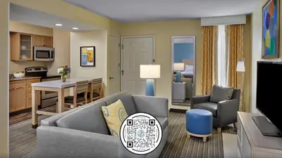 a living room with a couch and a table and a kitchen at Sonesta Simply Suites Dublin Columbus in Dublin