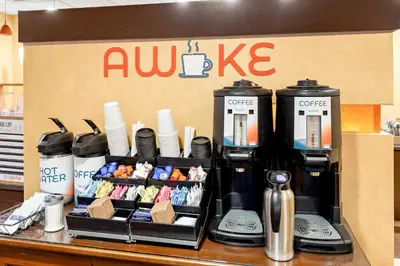 a table with a coffee machine and plates and cups at Sonesta ES Suites Charleston in Charleston