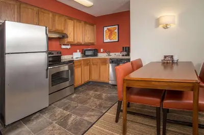 a kitchen with a table and a stainless steel refrigerator at Sonesta ES Suites Charleston in Charleston