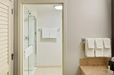 a bathroom with a shower and white towels at Courtyard Cincinnati Blue Ash in Blue Ash